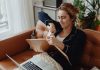 Jersey City resident blasts 15.5% tax hike, calls budget ‘irresponsible’ Woman in pajamas tearing paper on a sofa, expressing frustration. Indoors setting with laptop nearby.