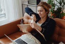 Jersey City resident blasts 15.5% tax hike, calls budget ‘irresponsible’ Woman in pajamas tearing paper on a sofa, expressing frustration. Indoors setting with laptop nearby.