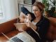 Jersey City resident blasts 15.5% tax hike, calls budget ‘irresponsible’ Woman in pajamas tearing paper on a sofa, expressing frustration. Indoors setting with laptop nearby.