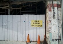 Abandoned building site with a warning sign and orange cones.