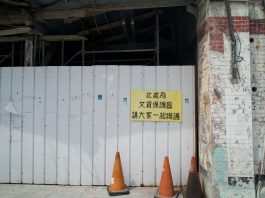 Abandoned building site with a warning sign and orange cones.