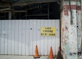 Abandoned building site with a warning sign and orange cones.