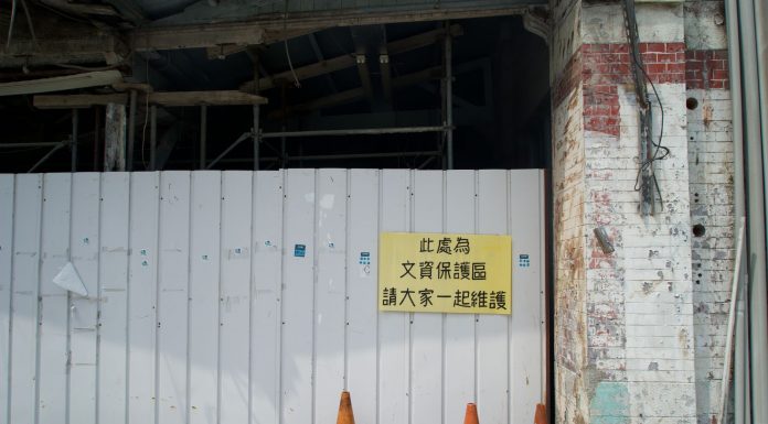 Abandoned building site with a warning sign and orange cones.