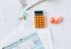 A flat lay image of tax forms, calculator, and office supplies on a desk.