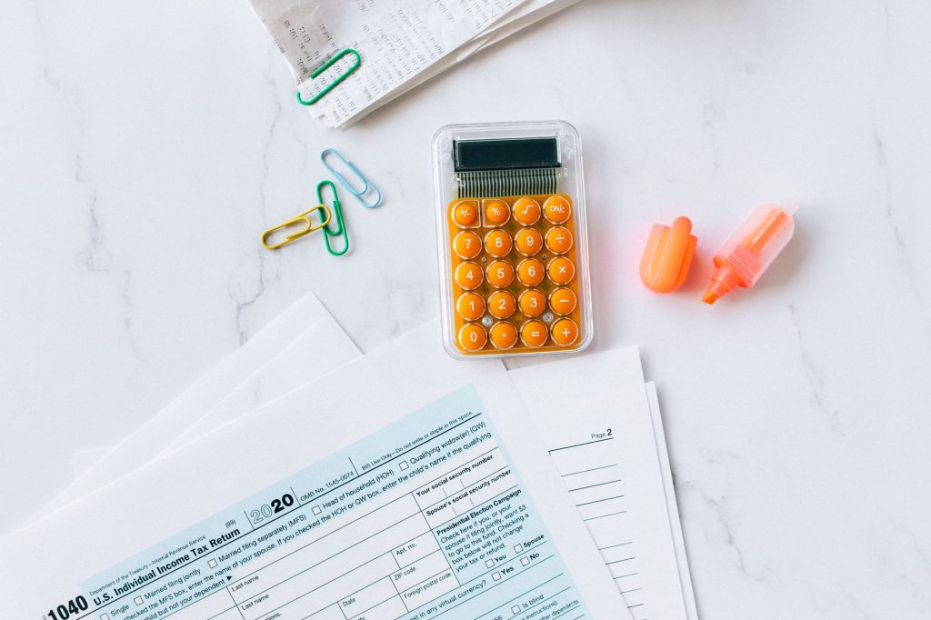 A flat lay image of tax forms, calculator, and office supplies on a desk.