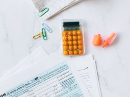 A flat lay image of tax forms, calculator, and office supplies on a desk.