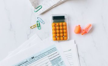 A flat lay image of tax forms, calculator, and office supplies on a desk.