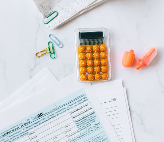 A flat lay image of tax forms, calculator, and office supplies on a desk.