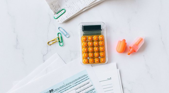 A flat lay image of tax forms, calculator, and office supplies on a desk.