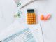 A flat lay image of tax forms, calculator, and office supplies on a desk.