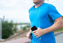 Jersey City’s Vyshyvanka Run Returns to Aid Ukraine Close-up of a man jogging outdoors holding a smartphone wearing earphones.
