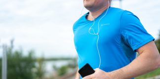 Jersey City’s Vyshyvanka Run Returns to Aid Ukraine Close-up of a man jogging outdoors holding a smartphone wearing earphones.
