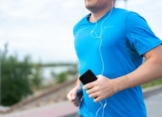 Jersey City’s Vyshyvanka Run Returns to Aid Ukraine Close-up of a man jogging outdoors holding a smartphone wearing earphones.