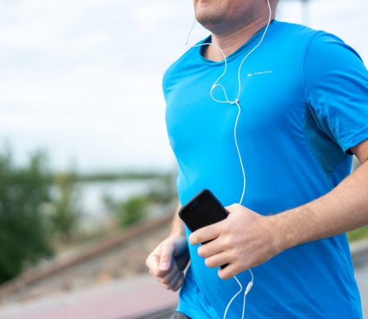 Jersey City’s Vyshyvanka Run Returns to Aid Ukraine Close-up of a man jogging outdoors holding a smartphone wearing earphones.