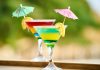 Los mejores lugares en Jersey City para bebidas congeladas este verano Vibrant cocktails with lemon slices and umbrellas, perfect for summer celebrations.