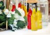 Colorful cocktail bottles with a white floral arrangement on a table setting.