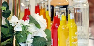 Colorful cocktail bottles with a white floral arrangement on a table setting.
