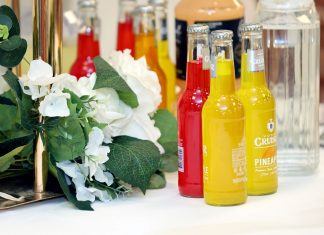 Colorful cocktail bottles with a white floral arrangement on a table setting.