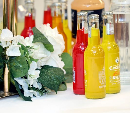 Colorful cocktail bottles with a white floral arrangement on a table setting.