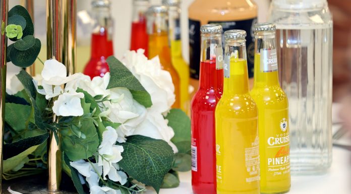 Colorful cocktail bottles with a white floral arrangement on a table setting.