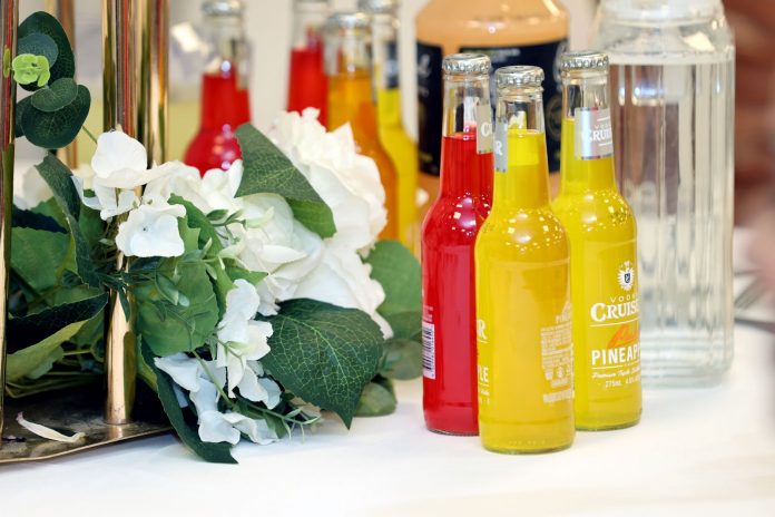 ltima-hora-50-cent-firmar-botellas-en-stew-leonar Colorful cocktail bottles with a white floral arrangement on a table setting.