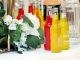 Colorful cocktail bottles with a white floral arrangement on a table setting.