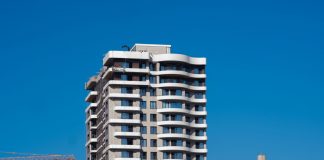 ÚLTIMA HORA: Aprobada torre de 27 pisos en Jersey City A view of a contemporary high-rise building against a clear blue sky in Bornova, İzmir, Türkiye.