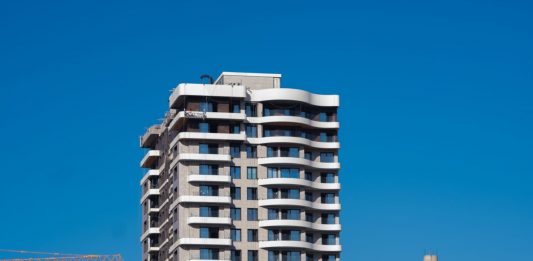 ÚLTIMA HORA: Aprobada torre de 27 pisos en Jersey City A view of a contemporary high-rise building against a clear blue sky in Bornova, İzmir, Türkiye.