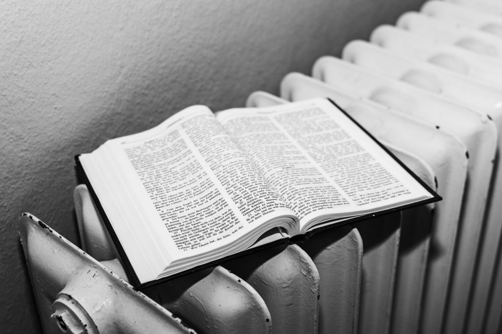 Open Bible on a radiator in black and white, symbolizing warmth and knowledge.