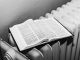 Open Bible on a radiator in black and white, symbolizing warmth and knowledge.