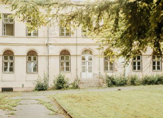 ÚLTIMA HORA: El histórico Griffith Building reabre en Newark A vintage building with arched windows and greenery in a peaceful setting.