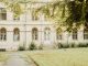 A vintage building with arched windows and greenery in a peaceful setting.