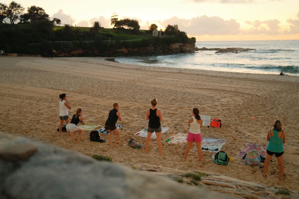 Women practicing yoga on Bondi Beach, Sydney, during a beautiful sunrise.