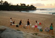 Women practicing yoga on Bondi Beach, Sydney, during a beautiful sunrise.