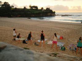 Women practicing yoga on Bondi Beach, Sydney, during a beautiful sunrise.