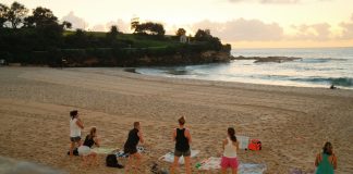 Women practicing yoga on Bondi Beach, Sydney, during a beautiful sunrise.