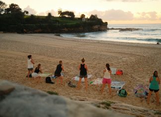 Women practicing yoga on Bondi Beach, Sydney, during a beautiful sunrise.
