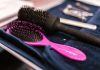 Close-up of pink and black hairbrushes on a towel in a salon setting.