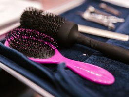 Close-up of pink and black hairbrushes on a towel in a salon setting.