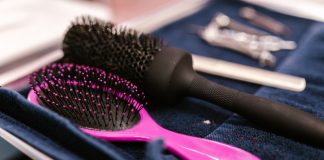 Close-up of pink and black hairbrushes on a towel in a salon setting.