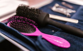 Close-up of pink and black hairbrushes on a towel in a salon setting.