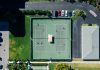 Drone shot showcasing tennis courts, parked cars, and residential area.