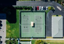 Drone shot showcasing tennis courts, parked cars, and residential area.