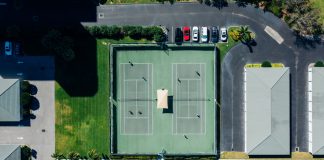 Drone shot showcasing tennis courts, parked cars, and residential area.