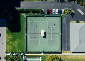 Drone shot showcasing tennis courts, parked cars, and residential area.