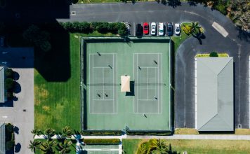 Drone shot showcasing tennis courts, parked cars, and residential area.