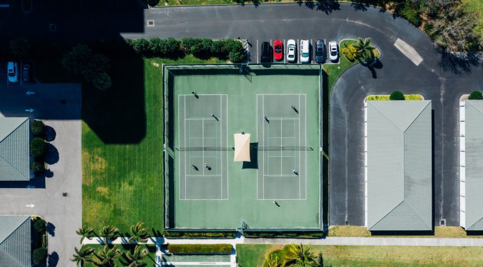 Drone shot showcasing tennis courts, parked cars, and residential area.