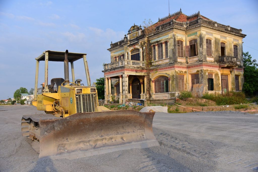 Historic building with a bulldozer outside on a construction site, under a clear sky.