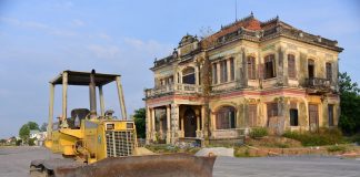 Historic building with a bulldozer outside on a construction site, under a clear sky.