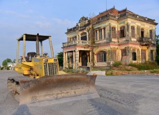 Historic building with a bulldozer outside on a construction site, under a clear sky.